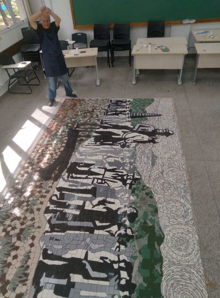 Javier Guerrero junto a un gran panel en mosaico en un espacio de formacion.