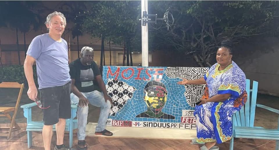 Javier Guerrero junto a un panel comunitario en mosaico, con participantes de la actividad.