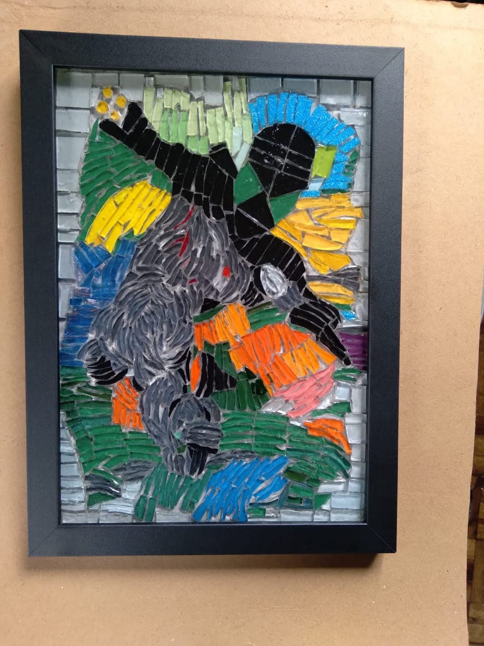 Obra en mosaico con colores intensos, montada en marco negro, del archivo aprobado del artista.