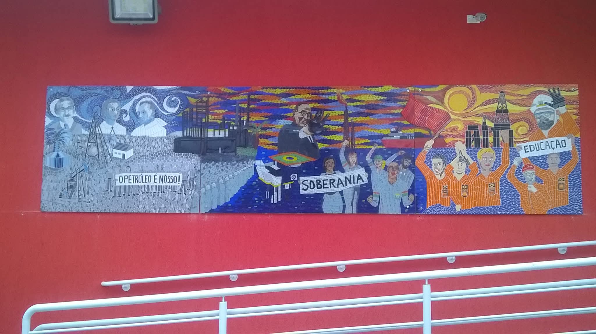 Panel mural en mosaico instalado sobre pared roja, del archivo aprobado del artista.