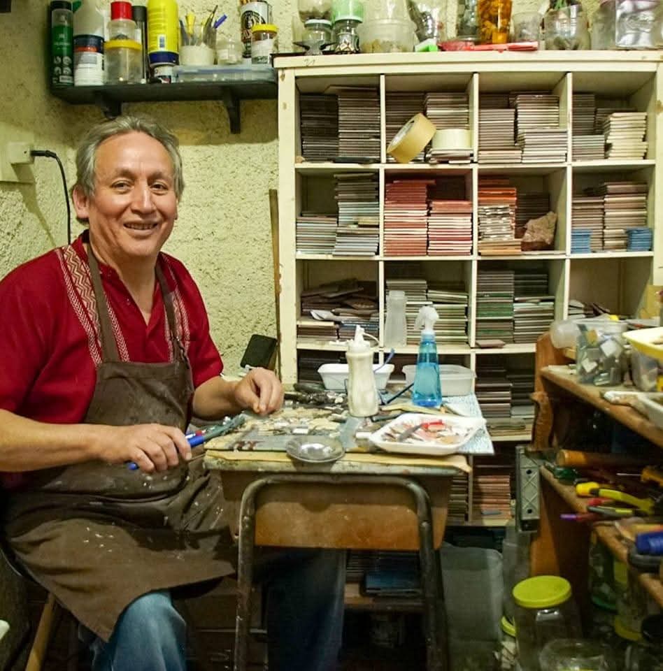 Javier Guerrero trabajando en el taller frente a estantes con teselas y herramientas.