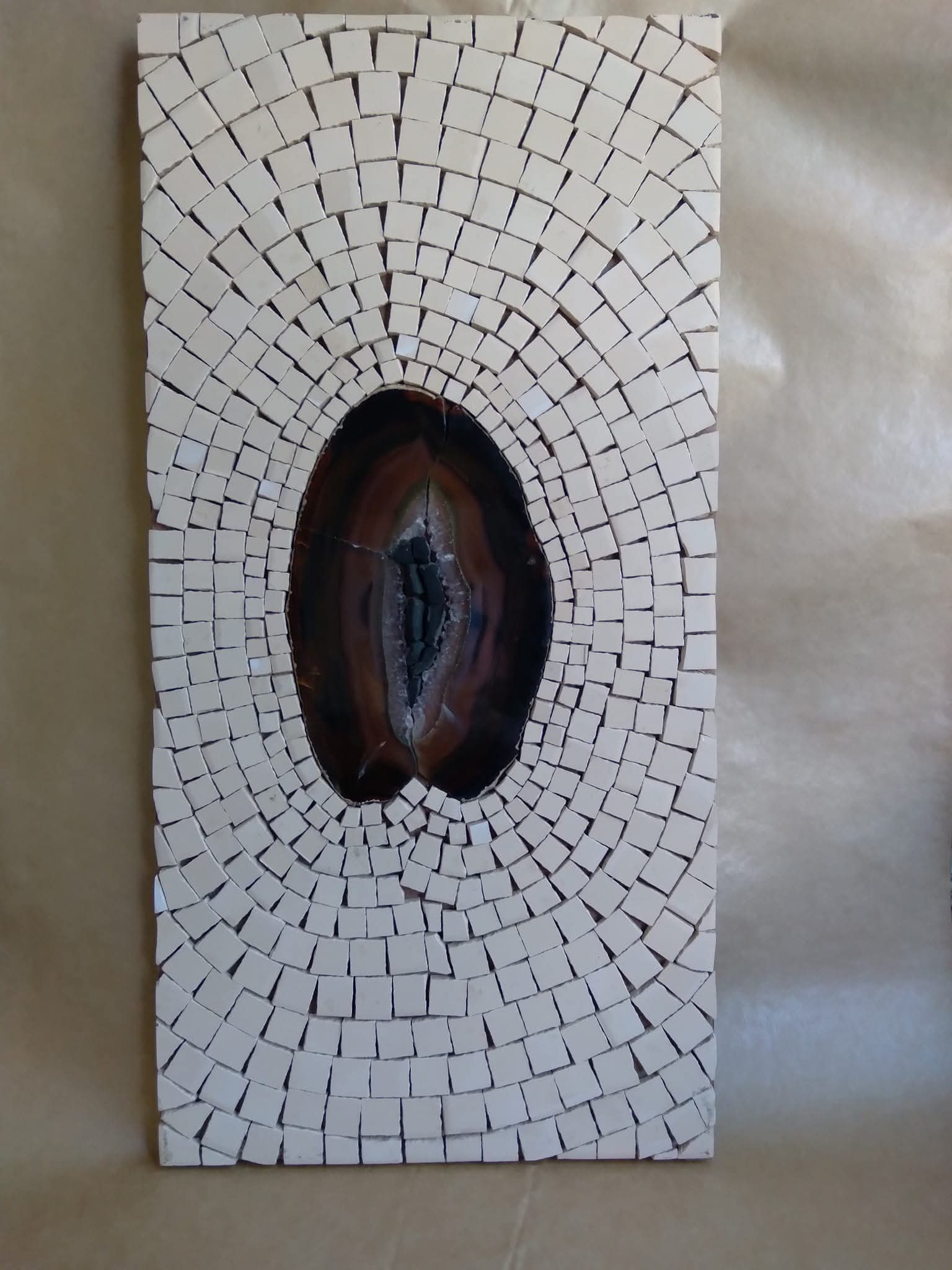 Obra en mosaico blanco con piedra central, del archivo aprobado del artista.
